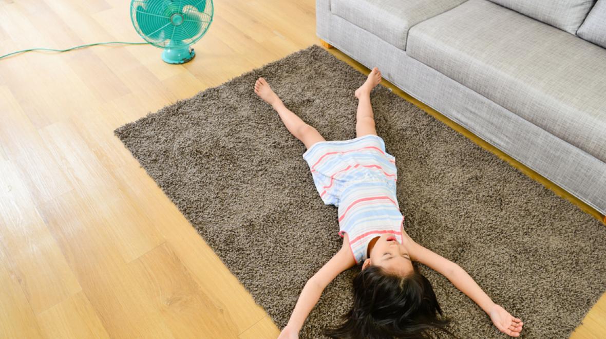 little girl lying on the floor in front of a fan