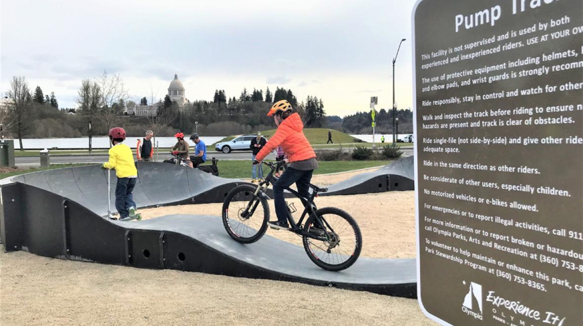 Kid in jacket riding his bike on the pump track at Olympia's Isthmus Park