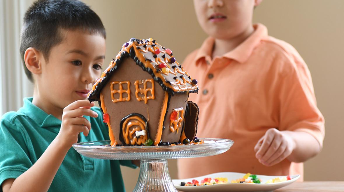 boys making a gingerbread house with halloween decorations