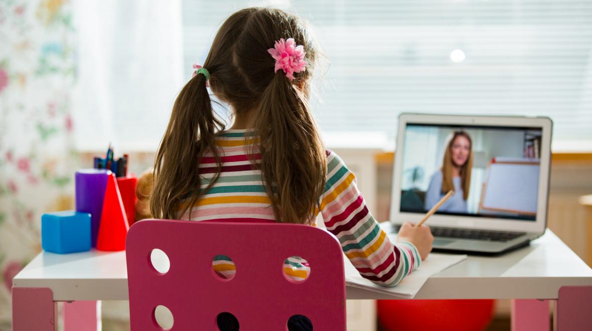 A young girl sits at her desk doing remote learning