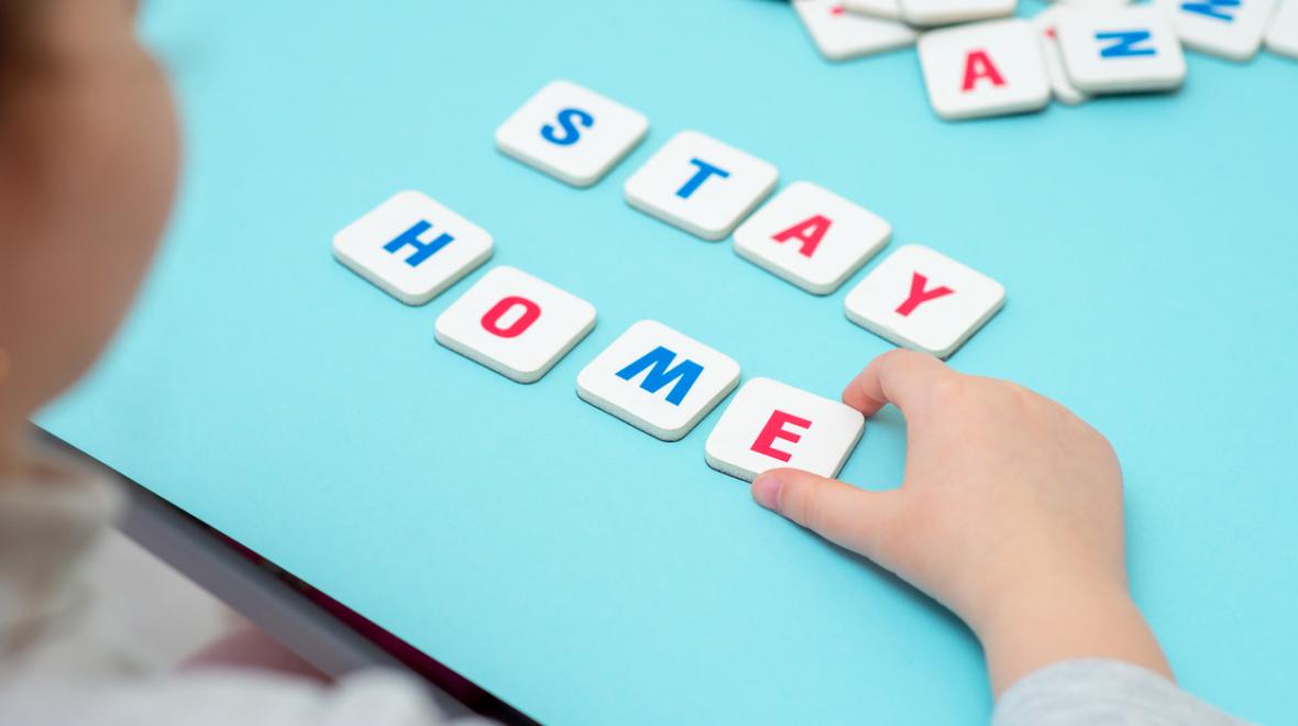 Girl spells out the words "Stay Home" with tiles