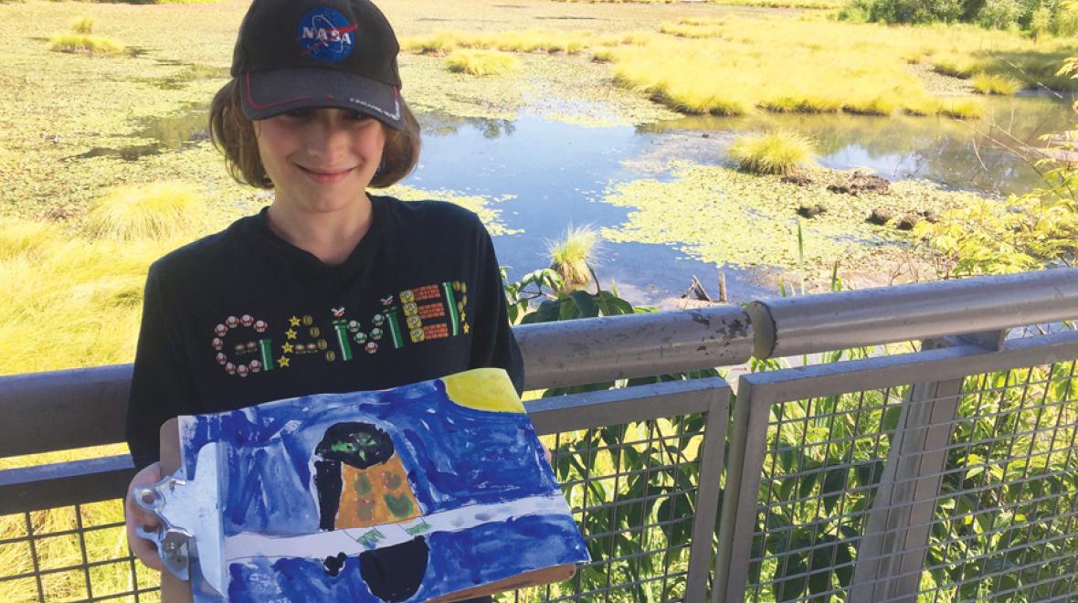 Boy outdoors proudly holding painting of a bird best nature crafts and walks for kids and families around Seattle