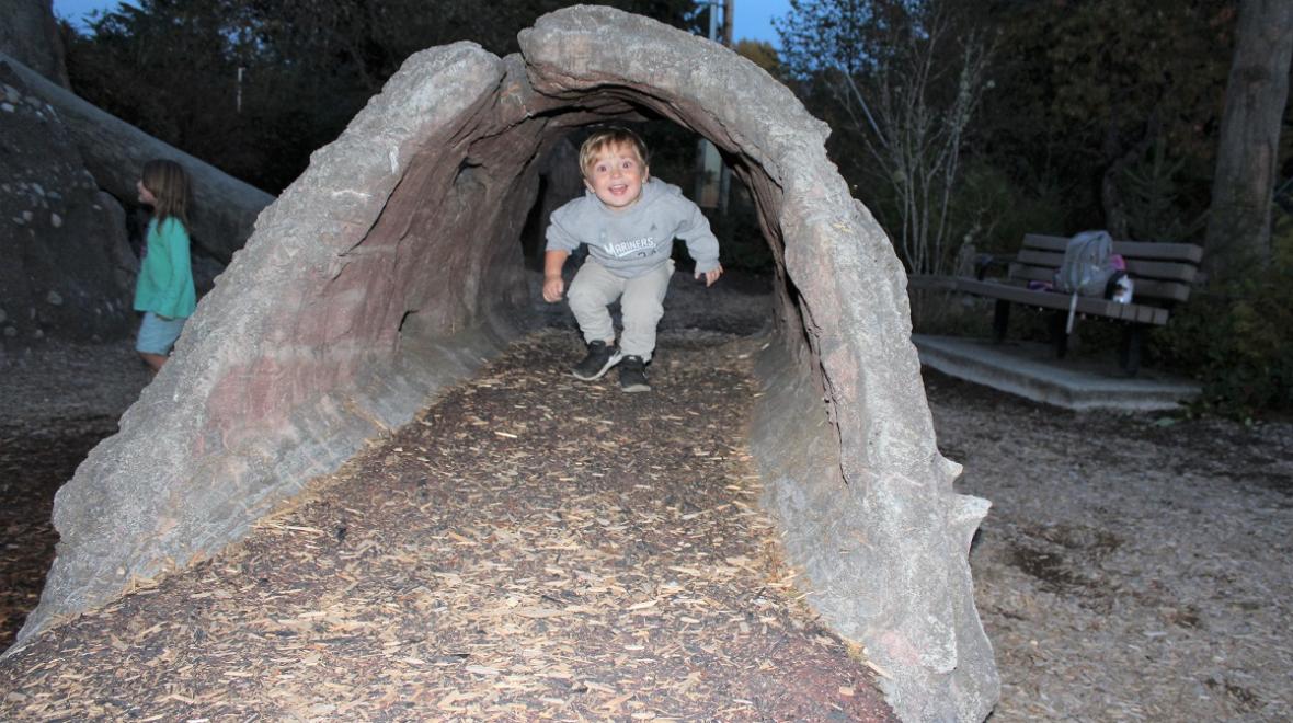 Boy smiling in a tunnel at Discovery Bay playground at Tacoma Nature Center