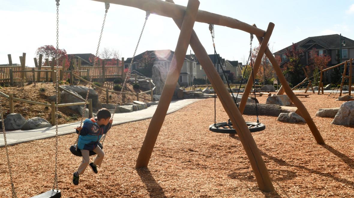Boy on swings at Mill Creek's Exploration Playground fun parks around the Seattle region