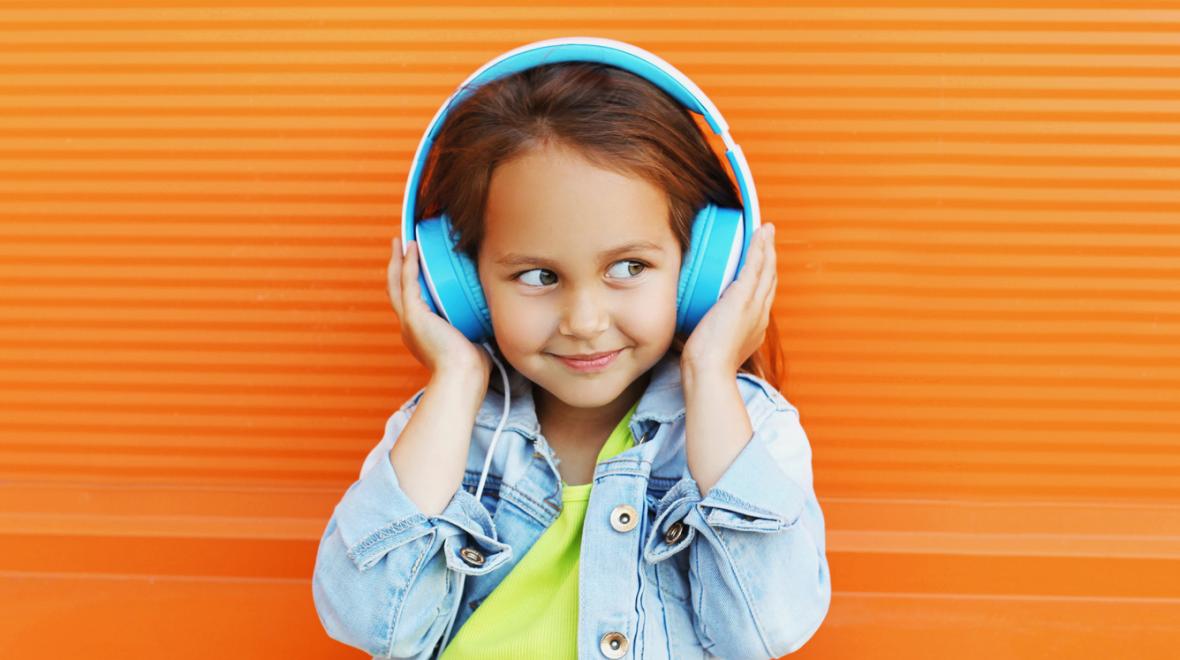 Smiling young girl listens to a podcast through headphones
