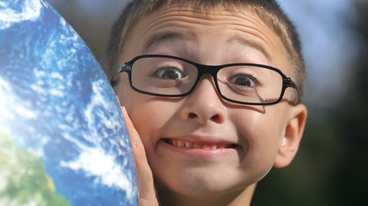 Cute boy with glasses holding up a globe