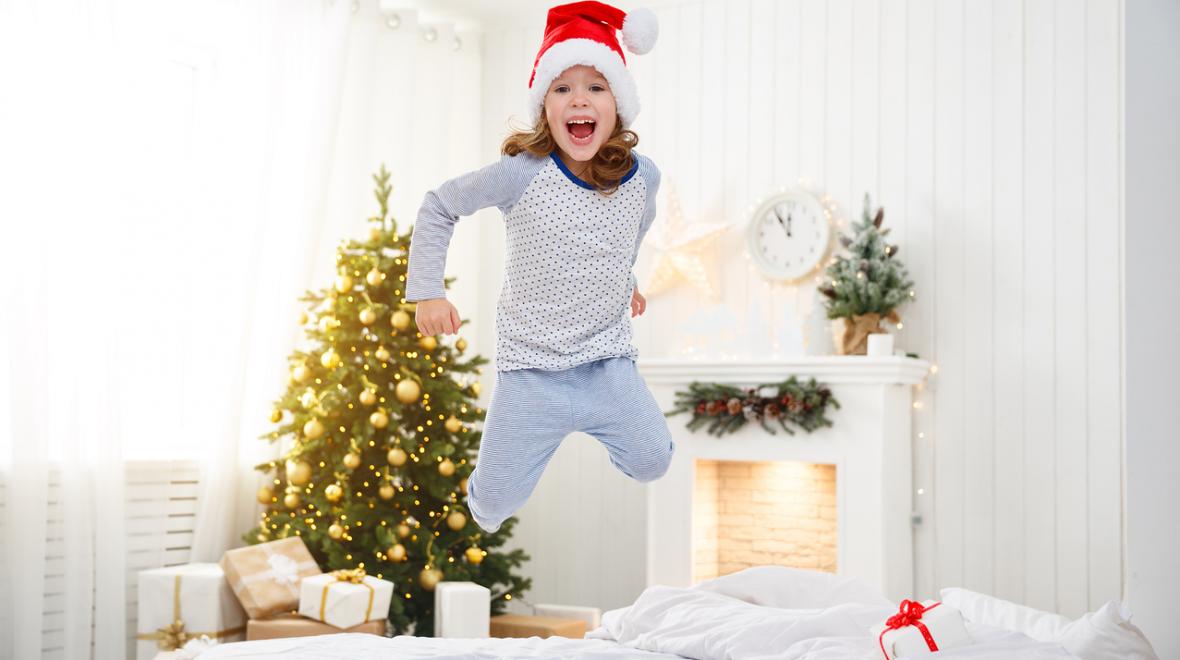 girl wearing a santa hat jumping on the bed