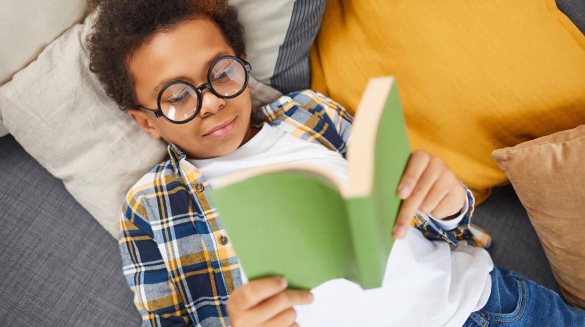 black boy with glasses reading a paperback