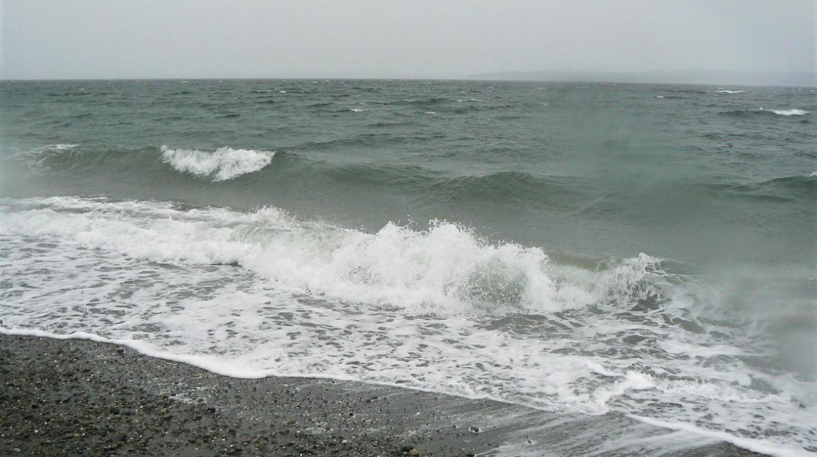 Waves breaking on the rocky shore of Marina Beach Park in Edmonds, Washington, near Seattle on a stormy, rainy, gray day