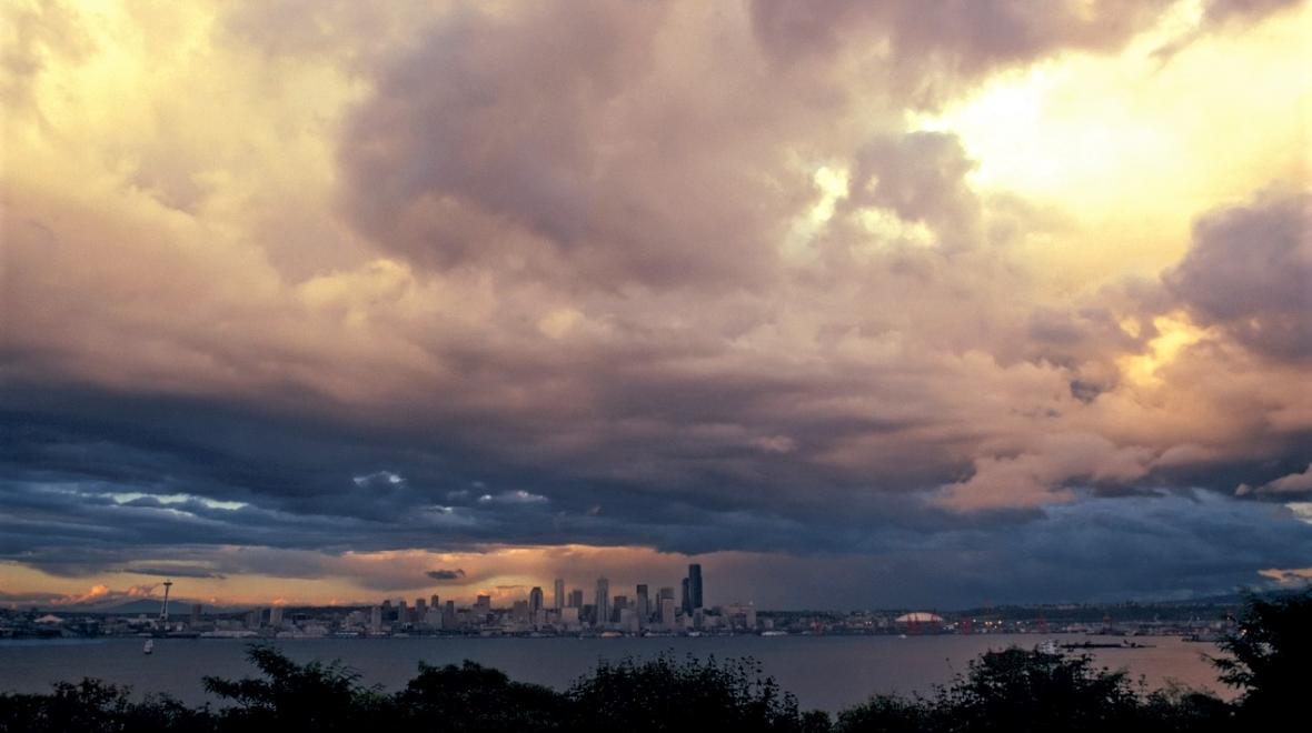 Huge winter storm clouds with small sun breaks seen over downtown Seattle viewed from West Seattle best places to experience bad weather with kids around Puget Sound