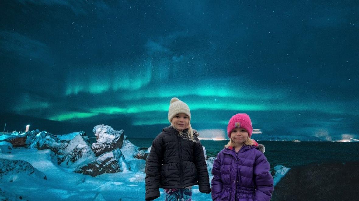 Two girls in winter coats and hats shown in front of a background of the Northern Lights seen in Iceland in this photoshopped virtual travel image
