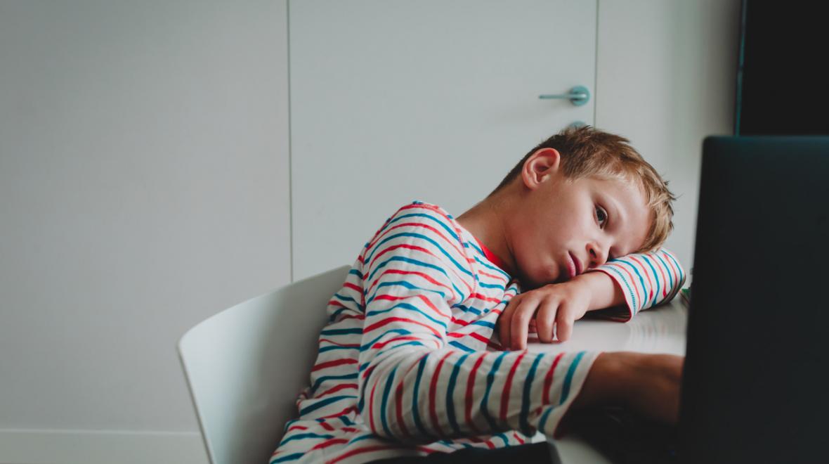 discouraged boy slumped on his desk in front of a computer