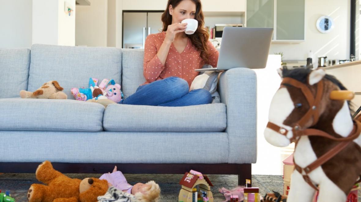 mother sitting on a couch surrounded by toys and clutter