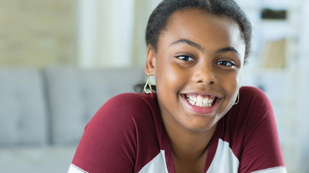 girl sitting indoors smiling at the camera