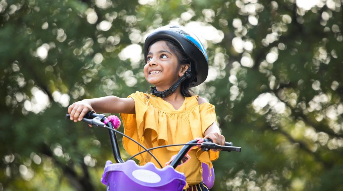 Cute girl about age 8 in yellow dress on bike with purple basket best spring break activities for seattle families