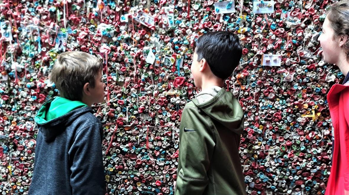 Tweens and teens stick their tongues out toward the Pike Place Market Gum Wall best instagram landmarks around Seattle