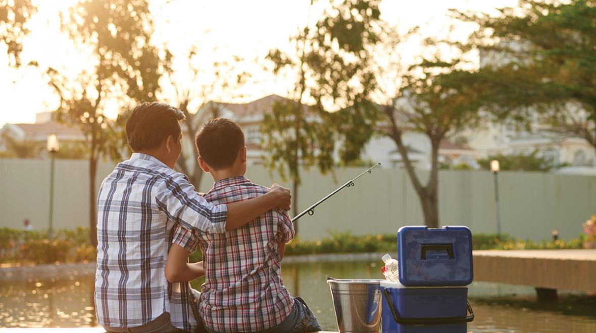 father and son sitting on a dock fishing together