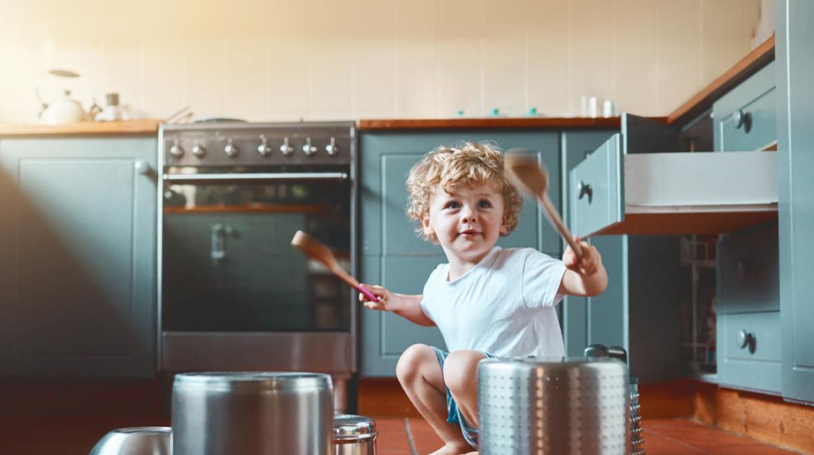 Portrait of an adorable little boy playing with pots in the kitchen