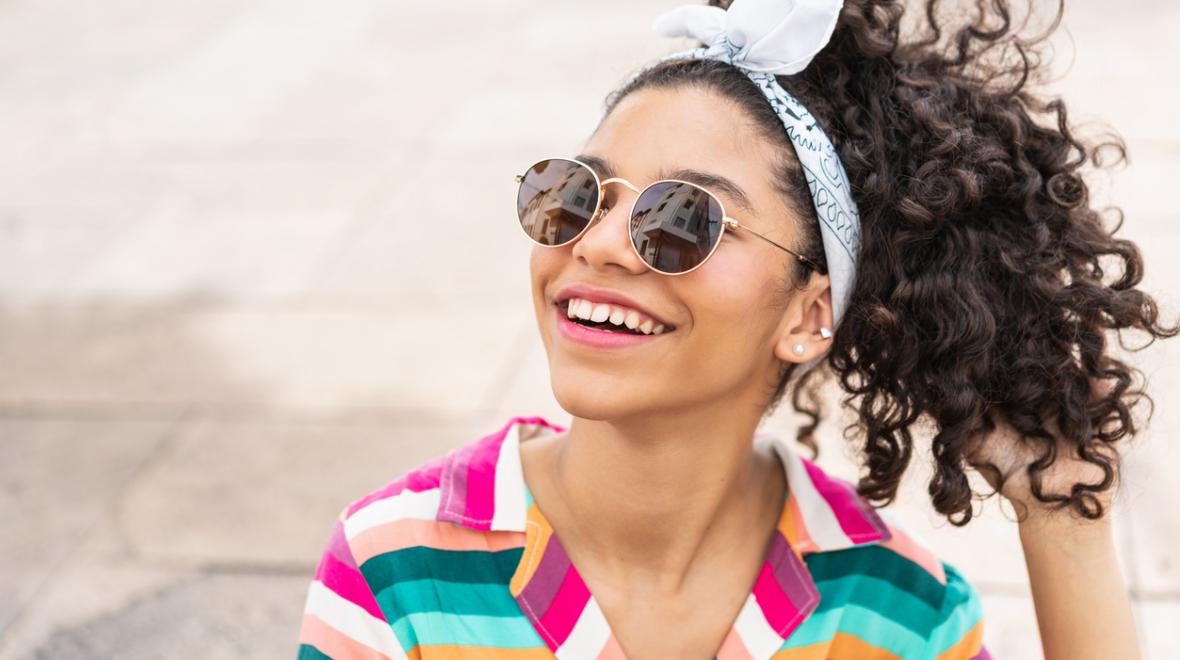 teen girl wearing sunglasses and a colorful striped shirt