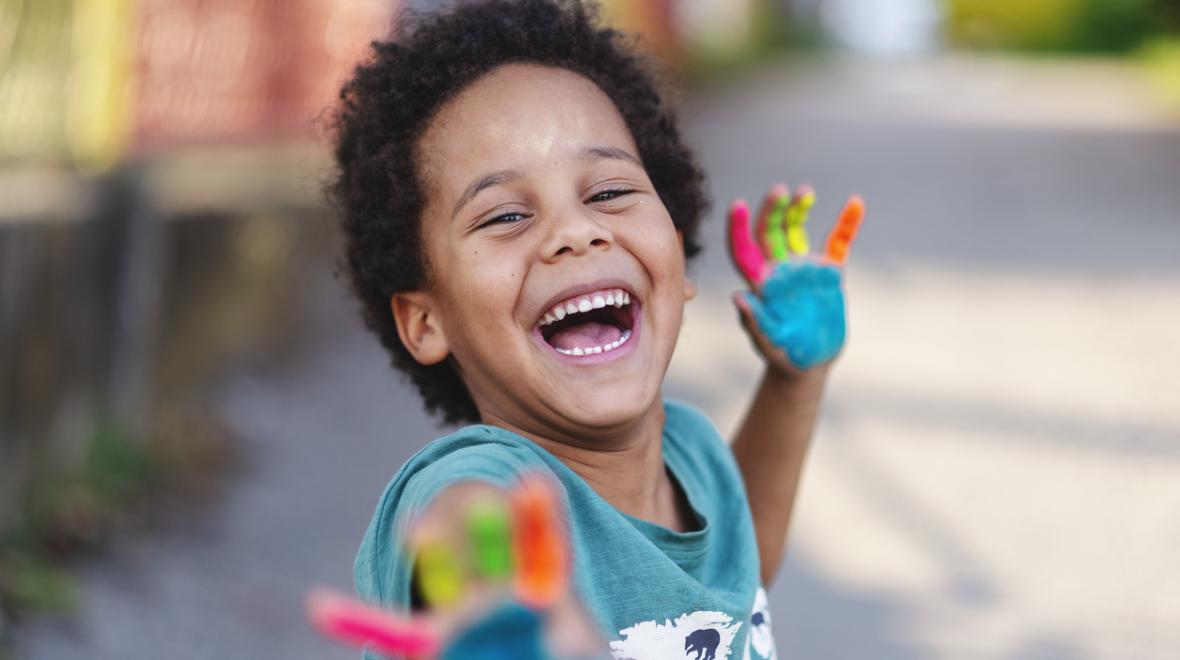 happy little boy with rainbow paint on his palms