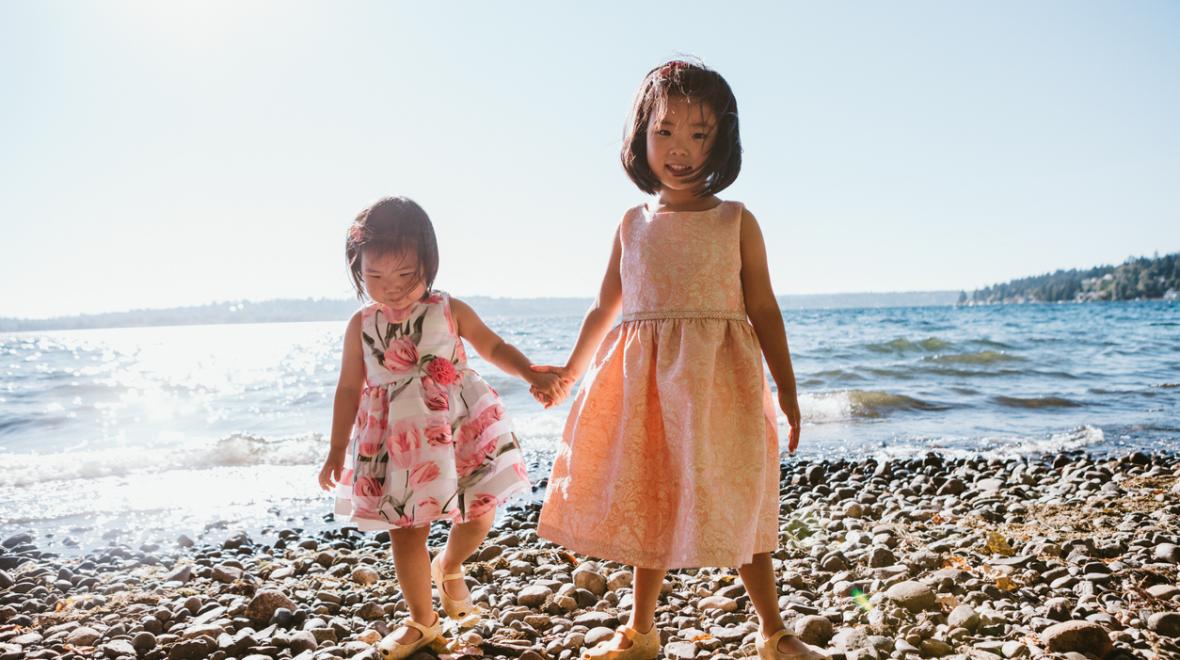 two little girls wearing cute summer dresses on a pacific northwest beach