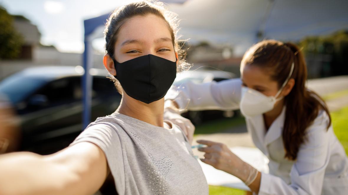 Teen girl taking a selfie while getting a vaccine