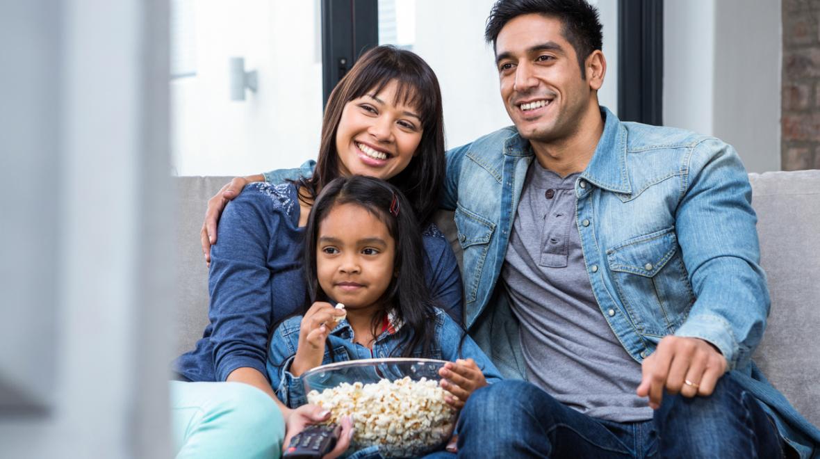 family sitting on a couch with popcorn and a remote