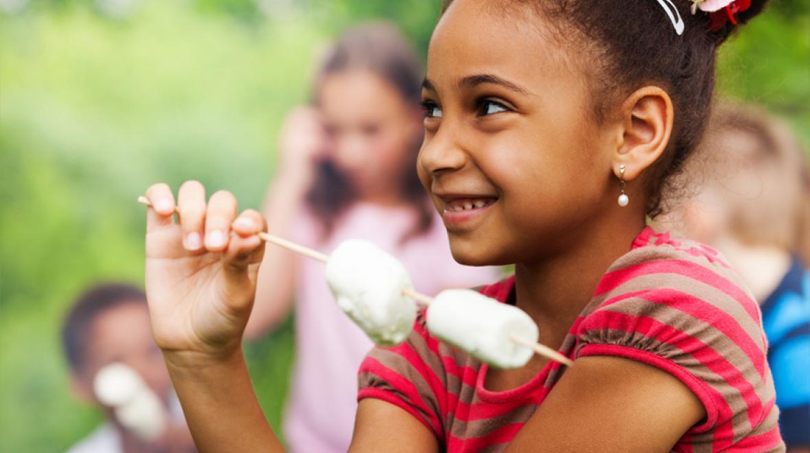 closeup of a girl holding marshmallows on a stick
