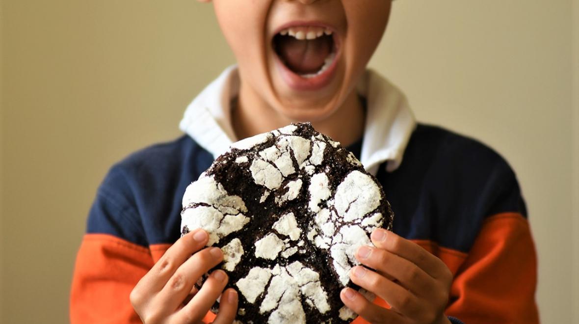 Kid with mouth open about to bite a large chocolate cookie he's holding with both hands My Friend's Cookies Seattle tasty treats worth finding with kids