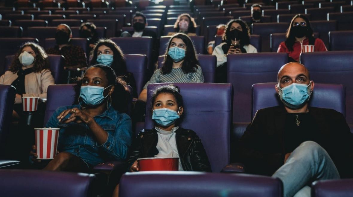Families and young people wearing masks while watching a movie in a movie theater summer 2021