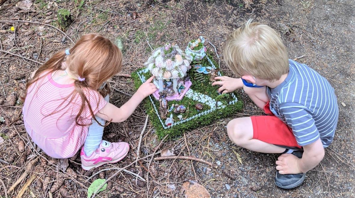 Young siblings inspect a fairy house found along the Pine Lake Fairy House Trail in Sammamish's Pine Lake Park near Seattle kids activities summer 2021
