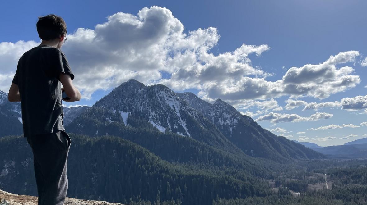 A youth hiker takes a water break and enjoys the view from the Garfield Ledges trail accessible from newly updated Middle Fork Snoqualmie Road near Seattle