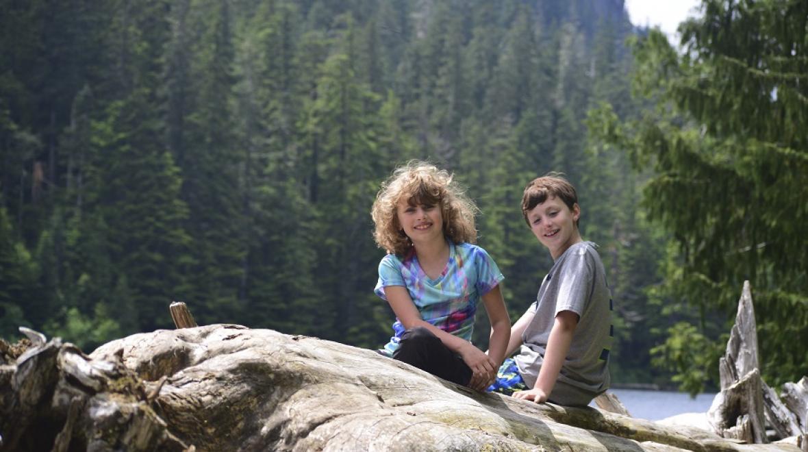A young brother and sister sit on a rock near Barclay Lake
