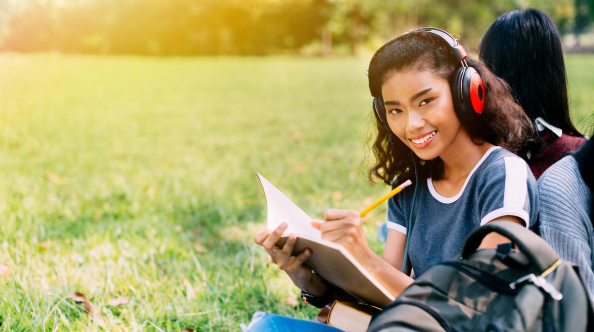 Young girl composing music in a park wearing headphones