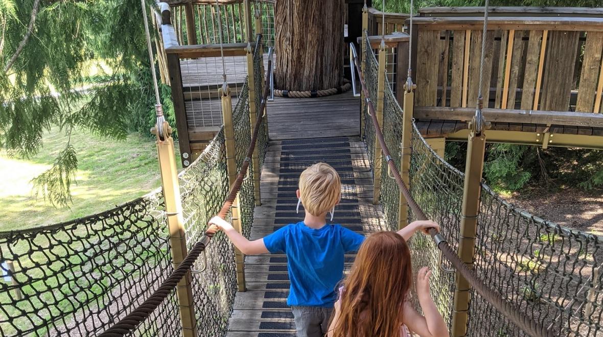 Kids crossing the suspension bridge to visit the Sammamish treehouse in Big Rock Park Central fun forts and treehouses for seattle kids and families