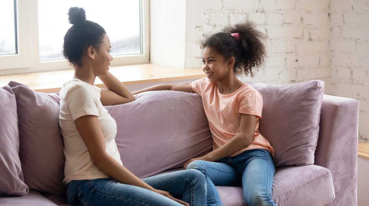 mother talking to her preteen daughter on a couch