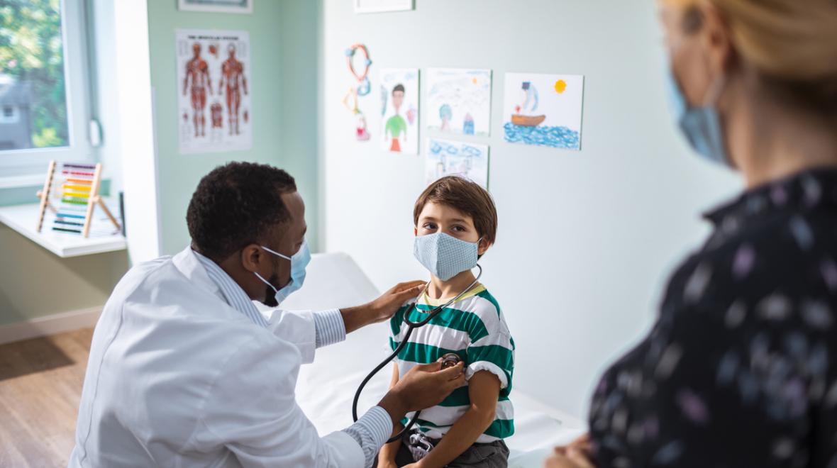 doctor listening to a child's heart with a stethoscope as the child's mother watches