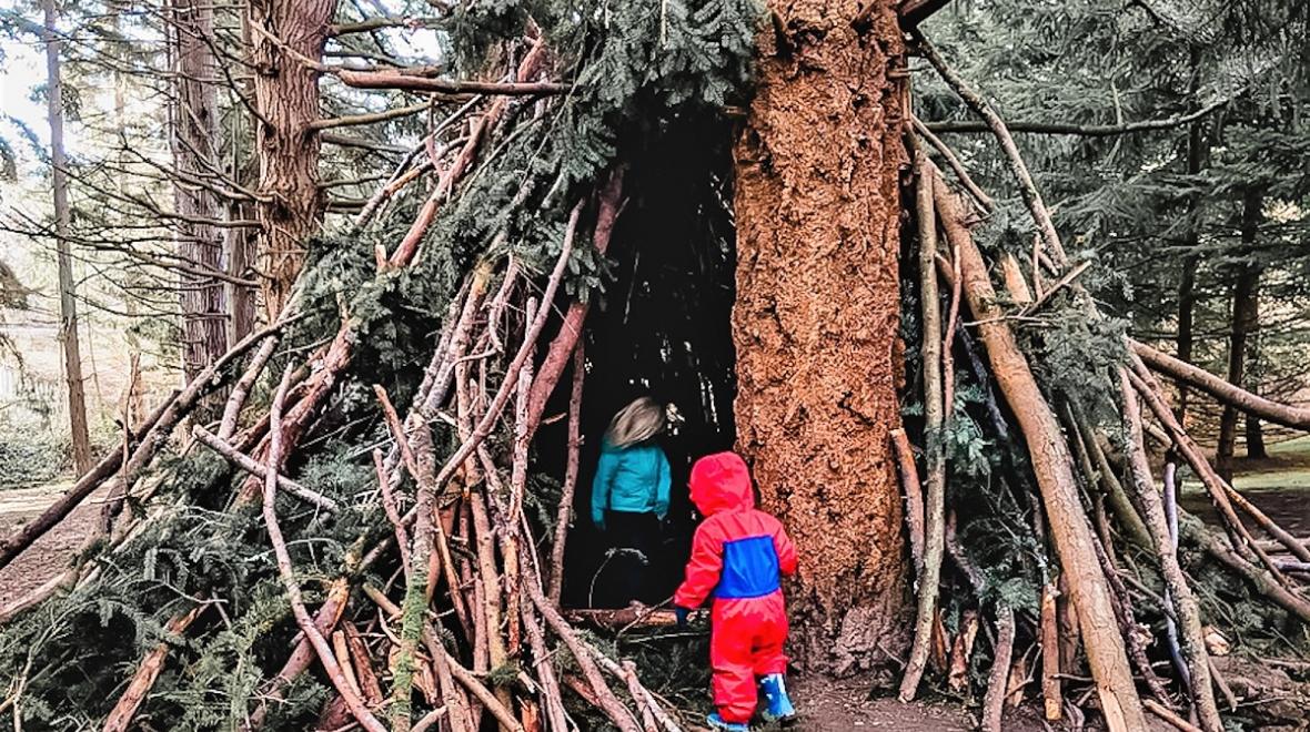 Kids peer into a large tree fort found near the playground at Seattle's Discovery Park, one of the Seattle area's largest and best parks