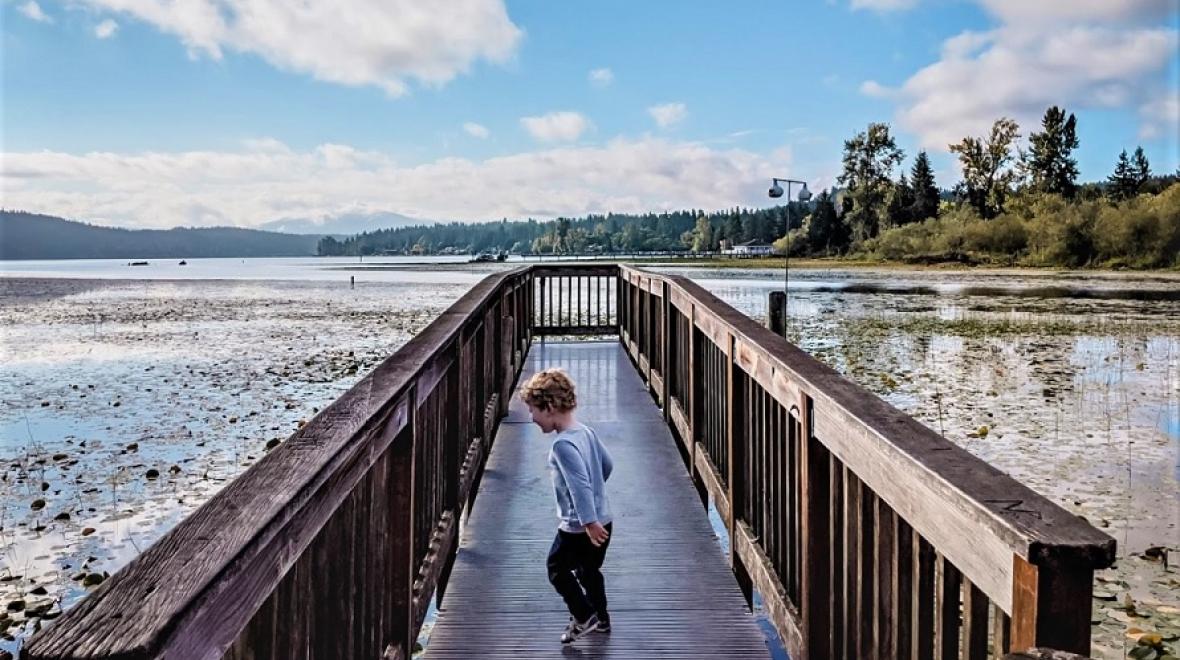 Boy on a boardwalk over Sammamish River Marymoor Park Audubon Bird loop best biggest parks around Seattle and Puget Sound