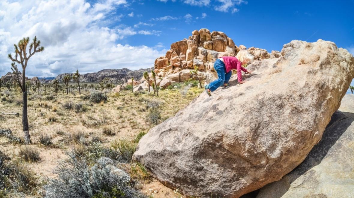 Girl climbing on rock formations at Joshua Tree National Park near Palm Springs best sunny destinations one nonstop flight from Seattle