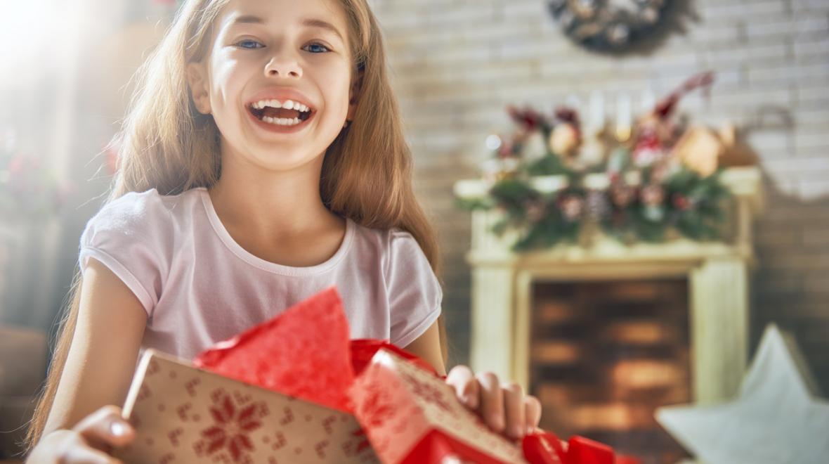 girl opening a gift with a fireplace in the background