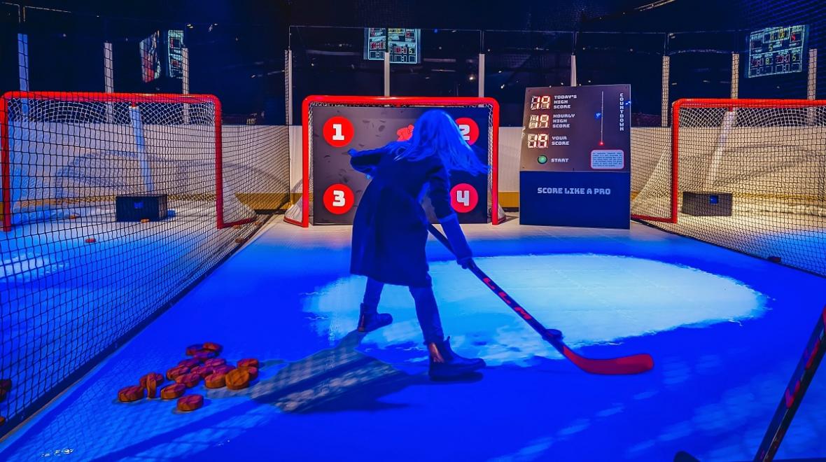 A young girl visiting an exhibit called Hockey Faster Than Ever at Seattle's Pacific Science Center shoots a goal at an interactive station