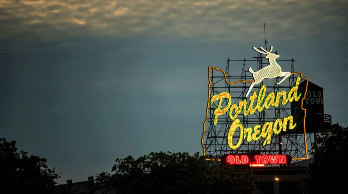 View of Portland Oregon's famious neon stag sign over Old Town seen at night Seattle family visit to Portland with kids