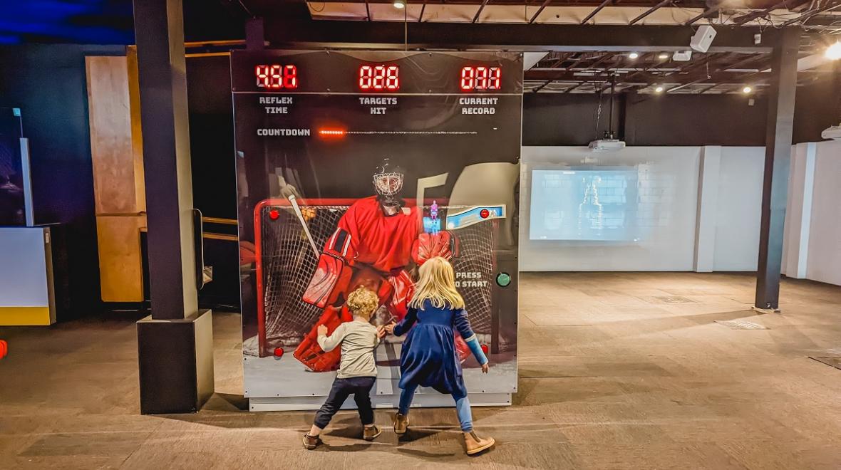 Two young kids test their goalie reflexes at Hockey: Faster Than Ever Pacific Science Center Seattle hockey exhibit winter break activities for families