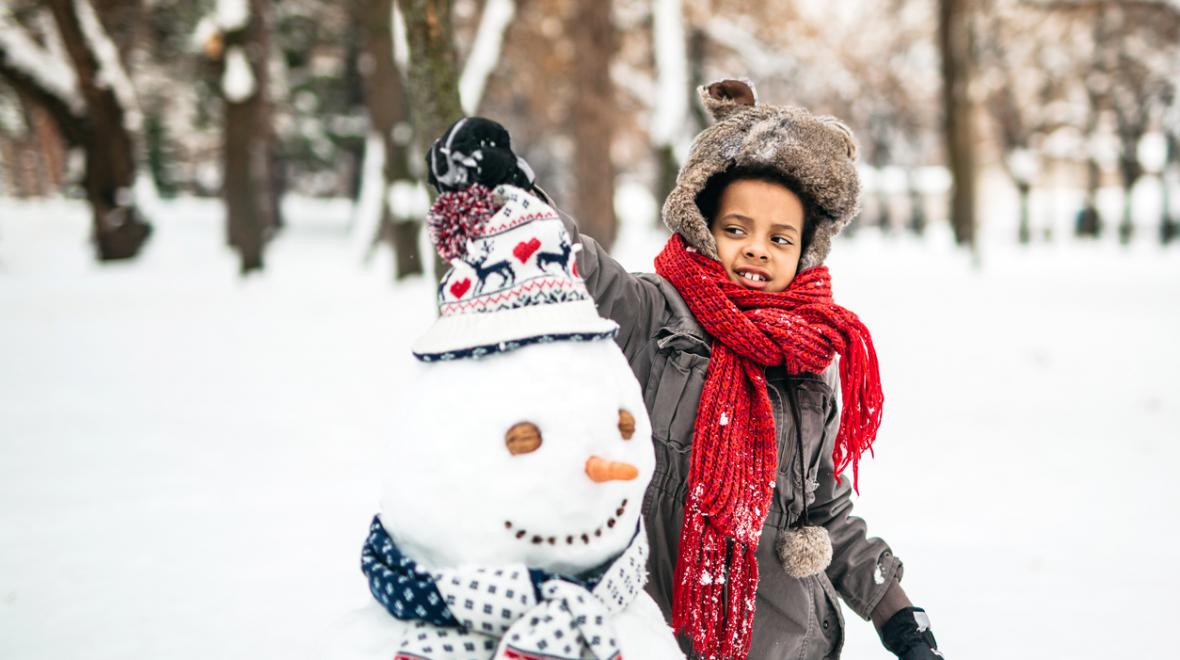 Young girl enjoying the winter by making a snowman