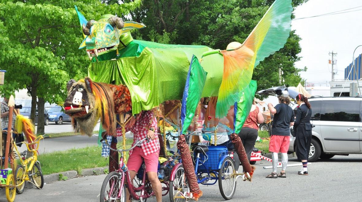 A green dragon float, powered by bicycles, is an entry in the 2017 Fremont Solstice Parade part of Seattle's annual Fremont Fair