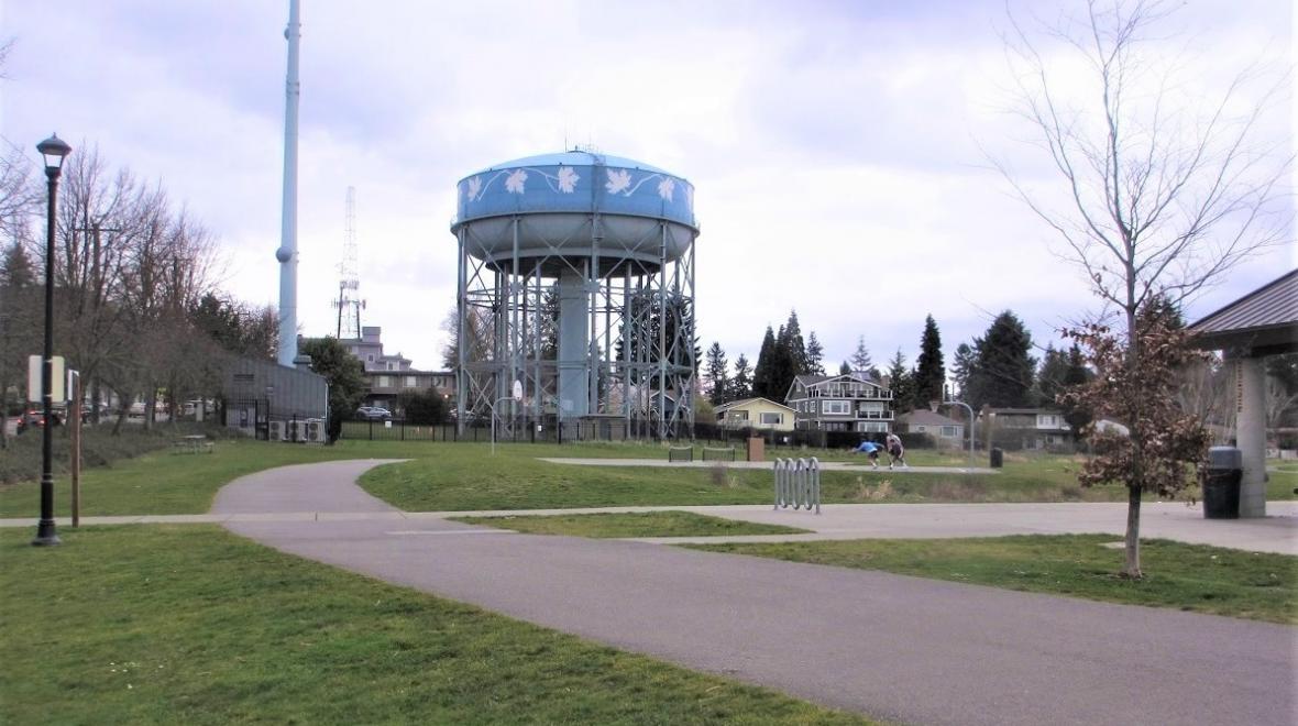 View of the bike path enciricling the upper level of Seattle's Maple Leaf Reservoir Park with the blue water tower in the frame
