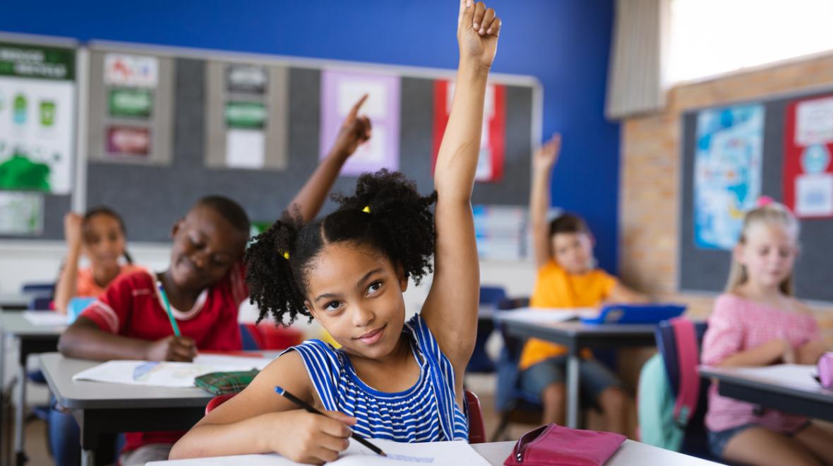 Young girl raising her hand in a classroom