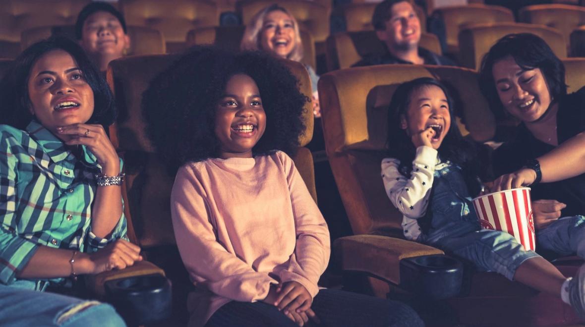 Happy kids in a movie theater watch a movie during cheap summer movie specials around Seattle