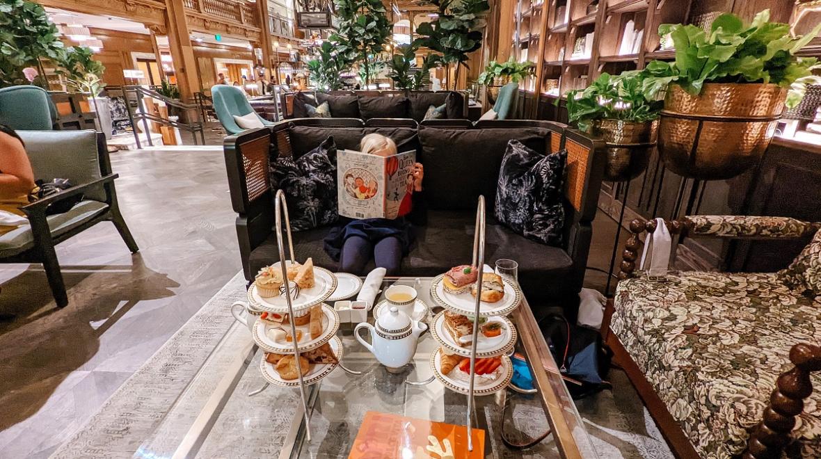 A girl reads a book while enjoying high tea in the lobby of Seattle's fancy Fairmont Olympic hotel